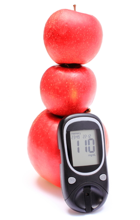 Stack of fresh red apples with glucose meter on white background, concept for healthy eating and diabetesの写真素材