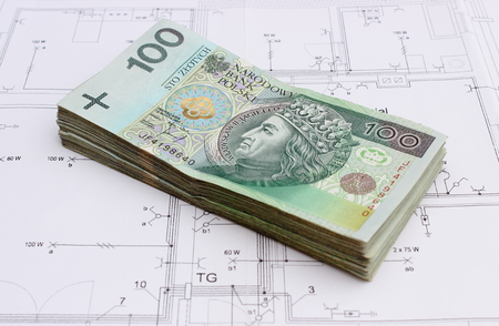 Heap of money lying on construction drawing of house, concept for building houseの写真素材