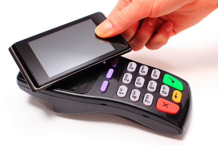Hand of woman paying with NFC technology on mobile phone, credit card reader, payment terminal,...