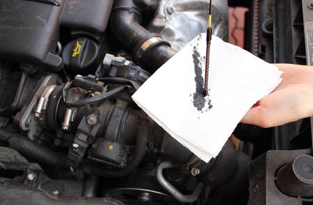 Auto mechanic checks the oil level in a car engineの写真素材