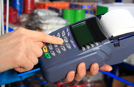 Hand of woman using payment terminal in an electrical shop, paying with credit card, credit card reader, finance conceptの写真素材