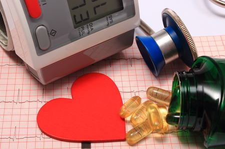 Medical stethoscope, instrument for measuring blood pressure, red heart shape and tablets on electrocardiogram graph, ekg heart rhythm, medicine conceptの写真素材