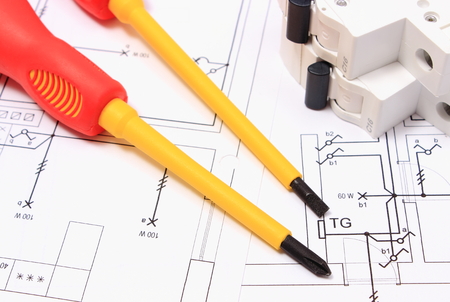 Screwdriver, work tools and electric fuse lying on construction drawing of house, accessories for...