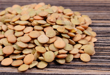 Heap of raw green lentil lying on wooden background, concept for healthy nutrition and eating