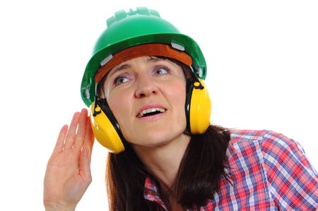 Female construction worker can not hear because wearing green helmet and protective headphones, safety at work and ear protection. White backgroundの写真素材