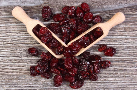 Heap of red cranberries with spoon on wooden table, concept for healthy nutrition and eating