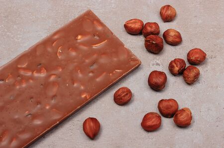 Nutritious chocolate and hazelnuts on structure of gray concrete