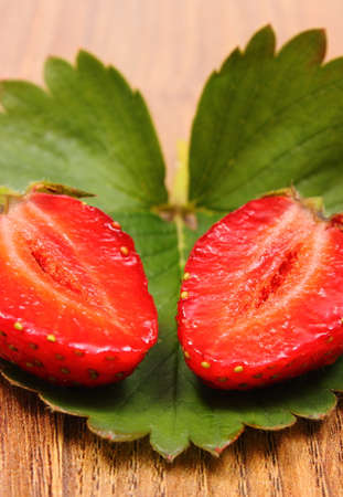 Fresh red strawberry with green leaves on wooden background, concept of healthy dessert