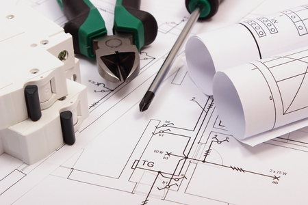 Metal pliers, screwdriver, electric fuse and rolls of diagrams on electrical construction drawing of house, work tool and drawing for projects engineer jobs, concept of building houseの写真素材