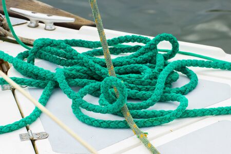 Yachting, green rope lying on deck of sailboat, details and part of yacht