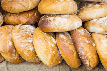 Heap of freshly baked traditional loaves of rye bread on stall at the bazaarの写真素材