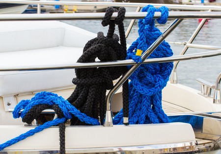 Yachting, coiled black and blue rope on deck of sailboat, details and part of yachtの写真素材