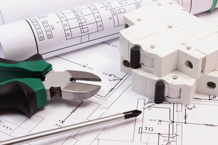 Metal pliers, screwdriver, electric fuse and rolls of diagrams on electrical construction drawing of...