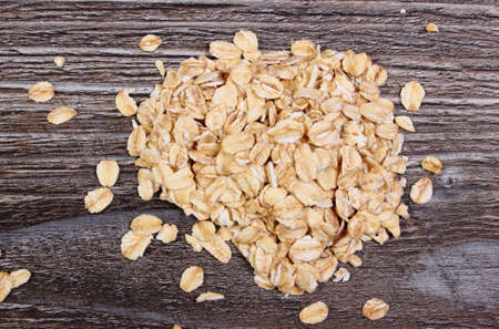 Heap of organic oatmeal, oat flakes on wooden background, concept for healthy eating and nutrition