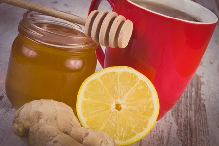 Vintage photo, Fresh lemon, honey in glass jar, ginger and cup of hot tea on old wooden white table, healthy food, strengthening immunity and alternative therapyの写真素材