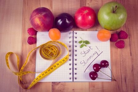 Vintage photo, Fresh fruits and vegetables with tape measure and notebook for writing notes, concept of slimming, diet and healthy nutritionの写真素材