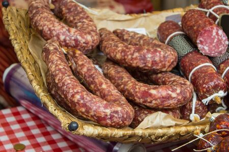 Heap of freshly prepared raw sausage with seasoning for sale in wicker basket on stall at the bazaarの写真素材
