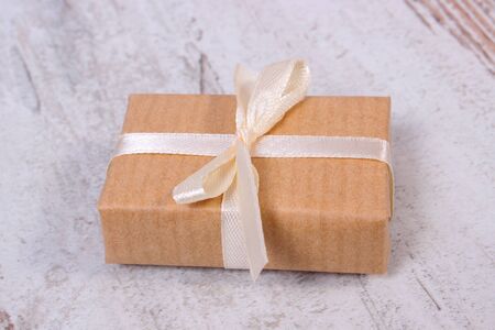 Wrapped gift for Christmas, birthday or other celebration on old wooden rustic background