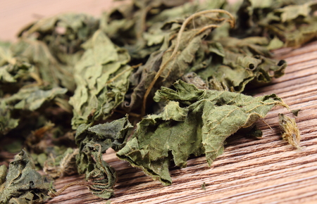 Heap of healthy dried nettle on wooden table, concept for healthy nutrition and herbalism