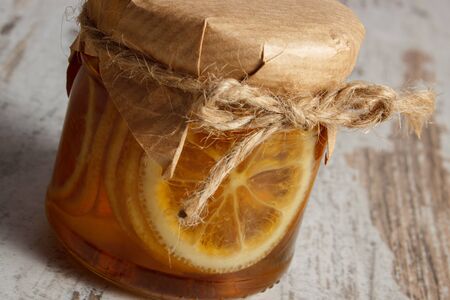 Lemon with honey in glass jar lying on old wooden white tableの写真素材