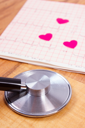 Hearts of paper and medical stethoscope lying on electrocardiogram graph, ecg heart rhythm, medicine and healthcare conceptの写真素材