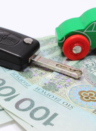 Heap of money, old wooden green toy car and key car. Isolated on white backgroundの写真素材