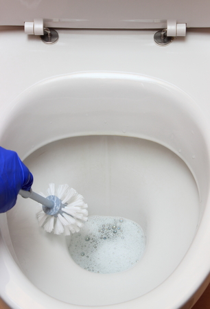 Hand of woman in blue glove cleaning toilet bowl, concept for house cleaning and household dutiesの写真素材