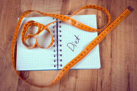 Vintage photo, Tape measure lying on notebook for writing notes, concept of slimming and dietの写真素材