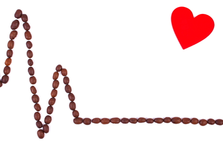 Electrocardiogram line of brown roasted coffee grains and red heart on white background, copy space for text, ecg heart rhythm, medicine and healthcare conceptの写真素材