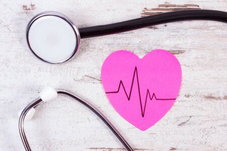 Pink heart of paper with electrocardiogram line and medical stethoscope on old wooden rustic background, ecg heart rhythm, medicine and healthcare conceptの写真素材