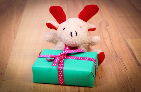 Plush reindeer and wrapped gift for Christmas, birthday, valentines or other celebration on wooden backgroundの写真素材