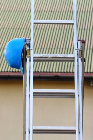 Protective blue helmet on aluminum ladder, concept of security and protection at workの写真素材