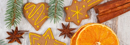 Fresh baked homemade decorated gingerbread, Christmas cookies with spices, green spruce branches on old white wooden background, christmas decorationの写真素材