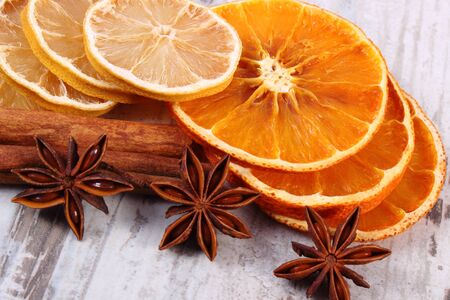 Slices of fresh dried lemon, orange and spices for cooking or baking lying on old rustic wooden backgroundの写真素材