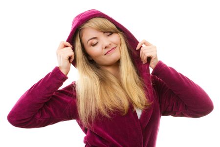Happy smiling and dreaming woman wearing fluffy purple bathrobe with hood on her head, enjoying freshness and wellbeingの写真素材