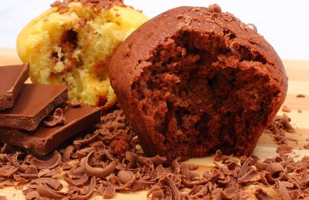 Delicious fresh baked muffins, grated chocolate and portion of chocolate lying on wooden cutting boardの写真素材