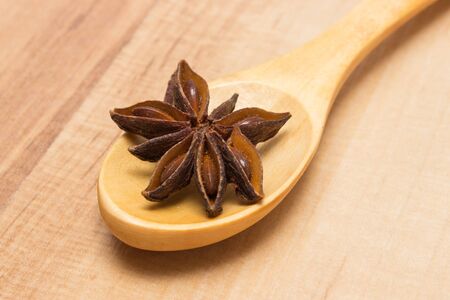 Star of anise on wooden spoon lying on wooden table, seasoning for cooking and bakingの写真素材