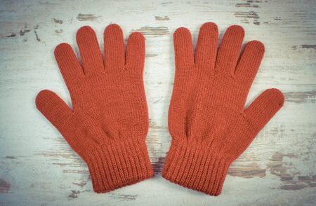Vintage photo, Pair of woolen gloves for woman on old rustic wooden background, womanly accessories, warm clothing for autumn or winter, burgundy colorの写真素材
