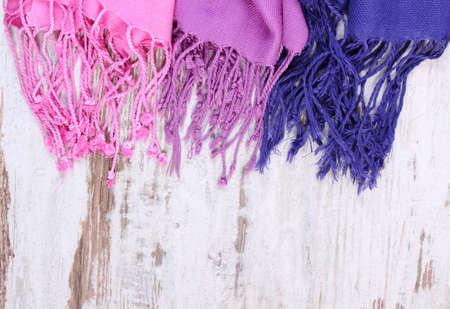 Colorful scarves with copy space for text, womanly accessories, warm clothing for autumn or winter, old rustic wooden backgroundの写真素材
