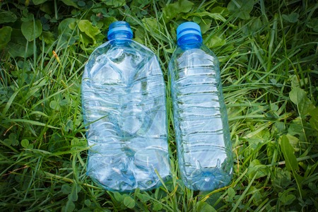 Crushed plastic bottles of mineral water on grass in park, concept of environmental protection, littering of environmentの写真素材