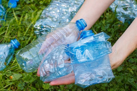 Hand of woman with crushed plastic bottles of mineral water, concept of environmental protection,...