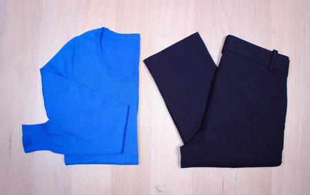 Womanly clothes on wooden surface plank, sweater and pants, warm clothing for autumn or winterの写真素材