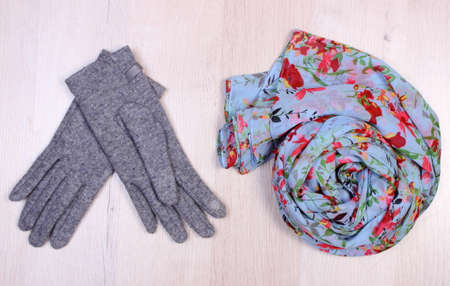 Womanly clothes on wooden surface plank, gloves and shawl or scarf, warm clothing for autumn or winterの写真素材