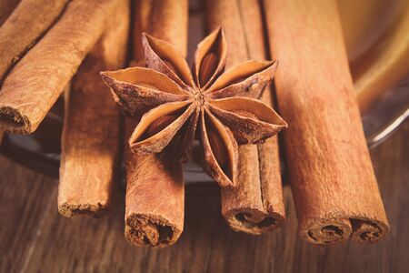 Vintage photo, Closeup of fresh star anise and fragrant cinnamon sticks on wooden surface plank,...