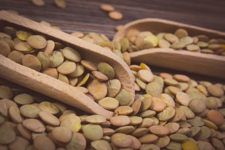 Vintage photo, Heap of raw green lentil with wooden spoon lying on wooden background, concept for healthy nutrition and eatingの写真素材