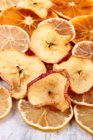 Slices of fresh dried lemon, orange and apple lying on old rustic wooden backgroundの写真素材