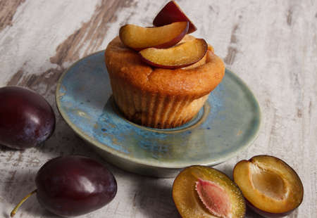 Homemade fresh baked muffins with plums on plate on old rustic wooden background, delicious dessertの写真素材