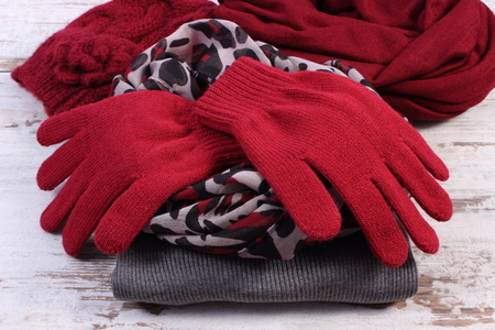 Woolen clothes for woman on old rustic wooden background, womanly accessories, gloves shawl sweater cap, warm clothing for autumn or winterの写真素材