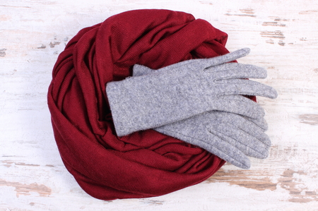 Pair of grey woolen gloves and burgundy shawl for woman on old rustic wooden background, womanly accessories, warm clothing for autumn or winterの写真素材