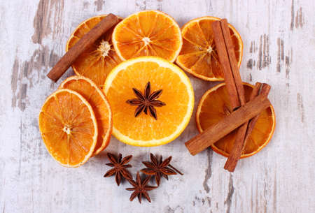 Slices of dried and portion of fresh orange with spices for cooking or baking on old rustic wooden background, healthy foodの写真素材